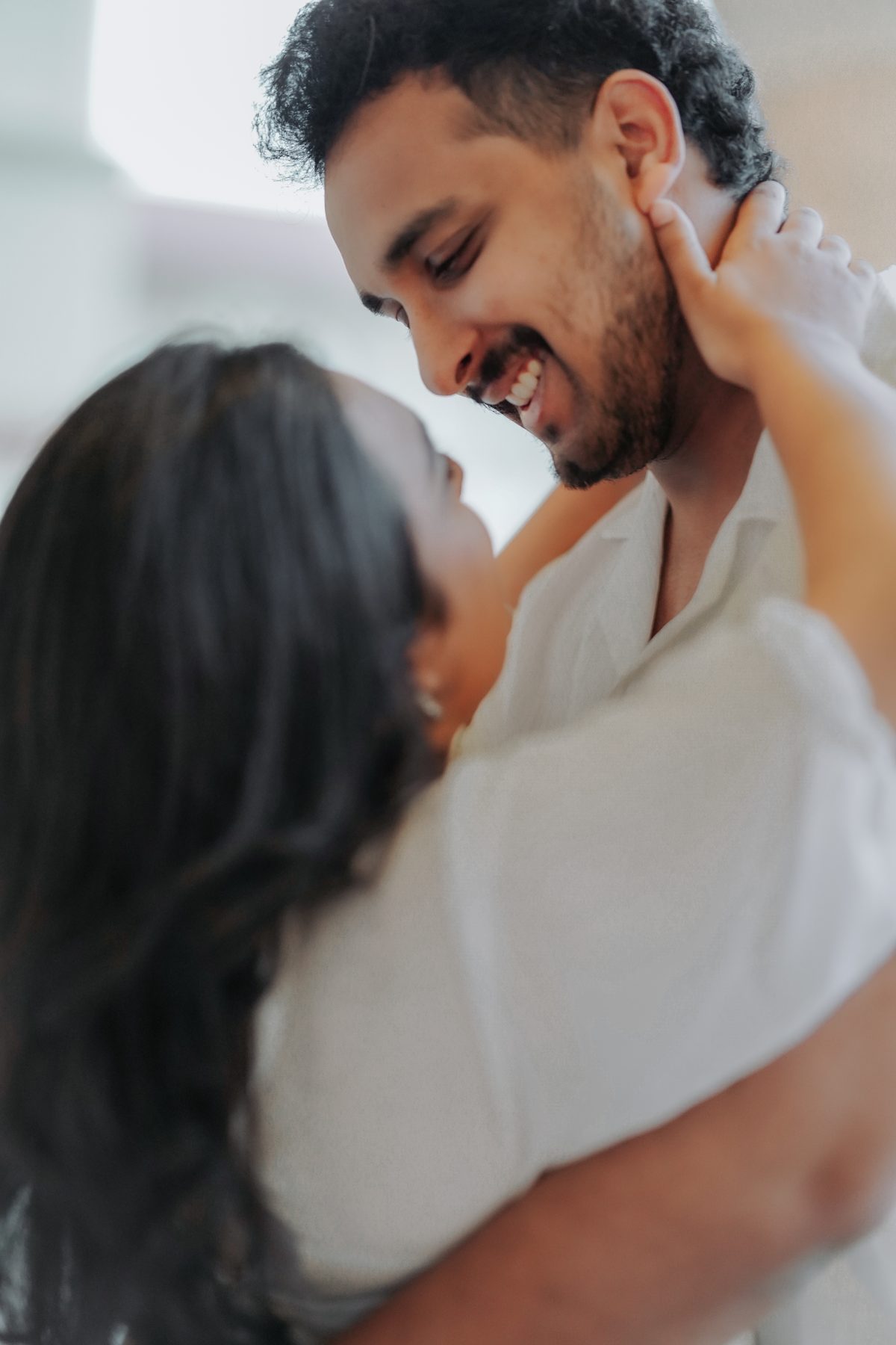 A couple close together, her hand at his face