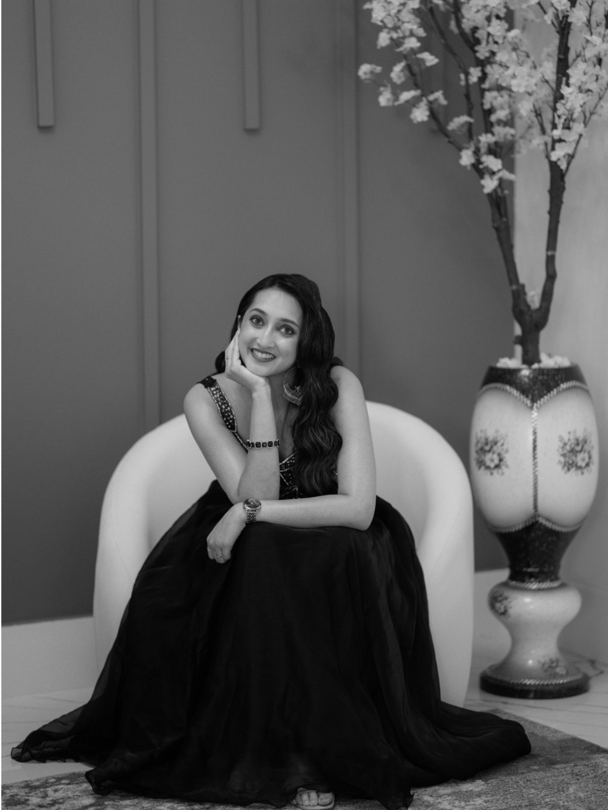 Black and white: a woman seated in a dark gown, chin on her hand