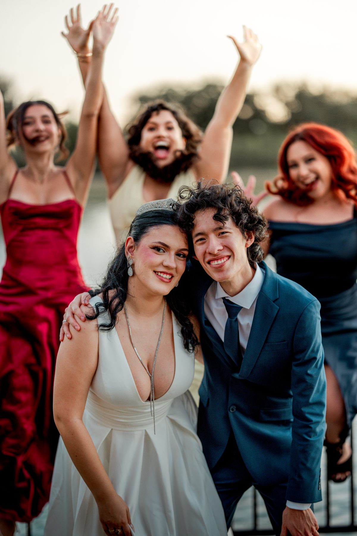 A wedding party cheering with their arms in the air