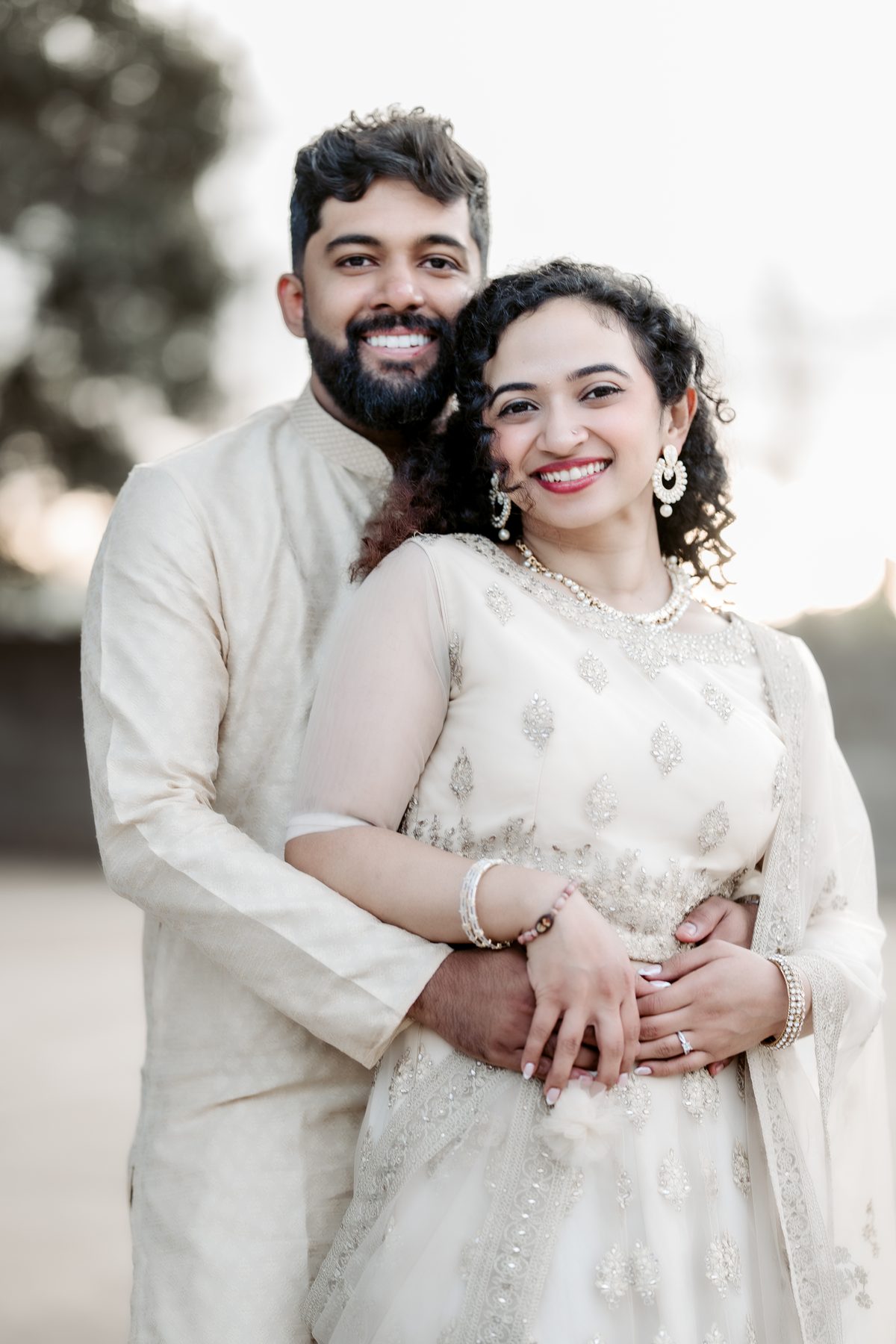 A couple in cream and gold, photographed in a garden