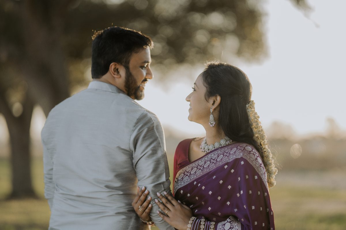 A couple under a large tree in golden light; she is in a purple saree